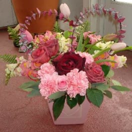 Pink and red floral arrangement in a white container with tulips and roses