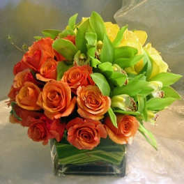 Bouquet of orange and yellow roses in a square glass vase