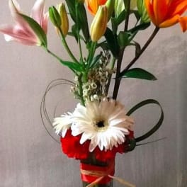 Tall bouquet of lilies and gerbera daisies in a clear glass vase