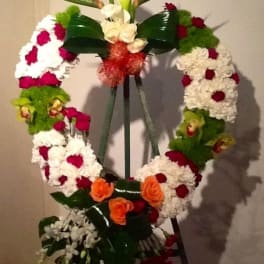 Standing floral wreath with white, red, green, and orange flowers on an easel