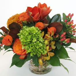 Orange and green mixed bouquet in a clear glass vase