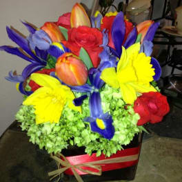 Bright mixed bouquet with red, yellow, blue, and orange flowers in a red box