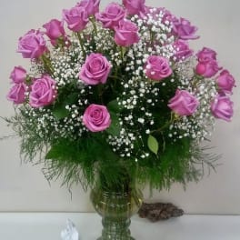 Pink roses arranged in a green glass vase with white baby's breath