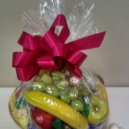Gift basket of assorted fruit wrapped in clear cellophane with a pink bow