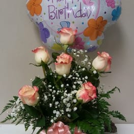 Birthday balloon above a vase of pink-edged roses