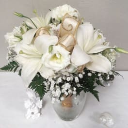 White floral bouquet in a clear glass vase with gold ribbon accents