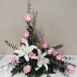 Pink roses and white lilies arranged with eucalyptus in a clear vase