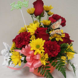 Birthday flower arrangement with red roses and yellow daisies in an orange pot