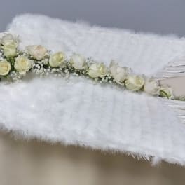 White rose floral arrangement with large white feather wings