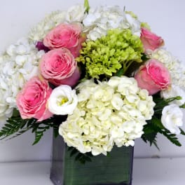 Pink roses and white hydrangeas in a square glass vase