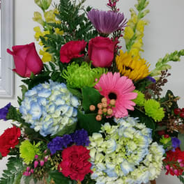 Colorful mixed flower arrangement in a basket with roses, hydrangeas, and gerbera daisies