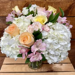 Bouquet of pastel roses, hydrangeas, and pink alstroemeria in a glass vase