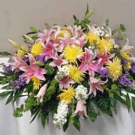Large casket spray with pink lilies, yellow chrysanthemums, and purple accents