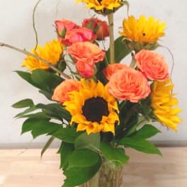 Sunflowers and peach roses in a clear glass vase
