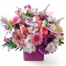 Mixed pink and white flower arrangement in a purple square vase