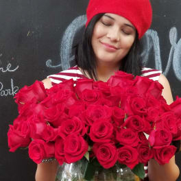 Woman holding a large bouquet of red roses in a glass vase