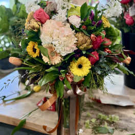 Mixed bouquet with pink, white, and yellow flowers in a glass vase
