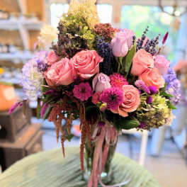 Bouquet of pink and lavender roses with mixed flowers in a glass vase