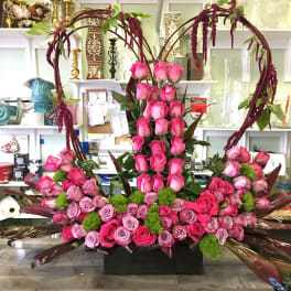 Large pink rose arrangement in a black container with heart-shaped arches