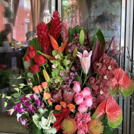 Large tropical flower arrangement with red roses, orchids, and anthuriums