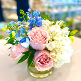 Pink roses with blue and white flowers in a glass vase