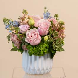 Pink roses and pastel flowers arranged in a white vase
