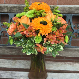Orange and peach bouquet in a glass vase