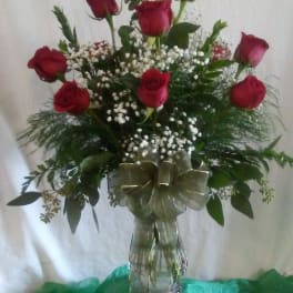 Red roses arranged in a clear glass vase with baby's breath