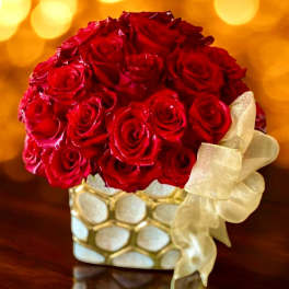 Red rose bouquet in a gold-and-white vase with a cream ribbon
