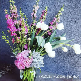 Tall pink and white floral arrangement in a glass vase