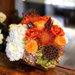 Compact bouquet of orange and white flowers with a lotus seed pod