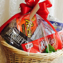 Basket of assorted candy wrapped in clear cellophane with a red bow
