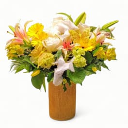Tall yellow and white mixed flower arrangement with pink lilies in a burlap-wrapped vase