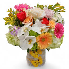 Mixed bouquet of roses, orchids, and gerbera daisies in a burlap-wrapped vase