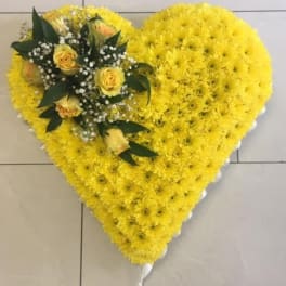 Heart-shaped yellow floral arrangement with yellow roses and dark greenery