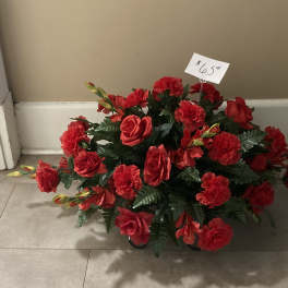 Red rose and carnation arrangement in a low container with a price tag