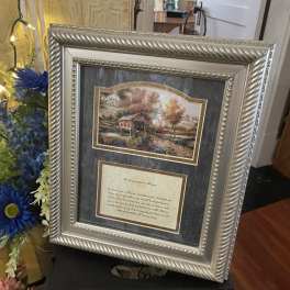 Framed memorial print with blue and pink flowers beside it