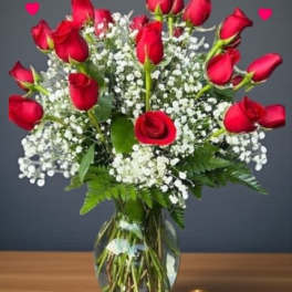 Red roses arranged in a clear glass vase with white baby's breath