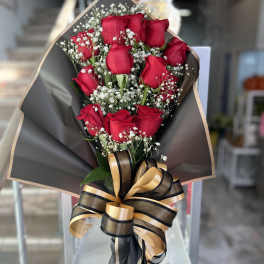 Bouquet of red roses with baby's breath and a black-and-gold ribbon