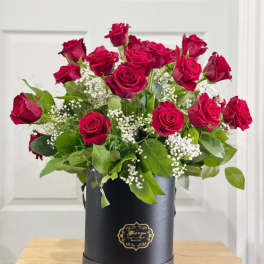 Red roses arranged in a black hat box with baby's breath