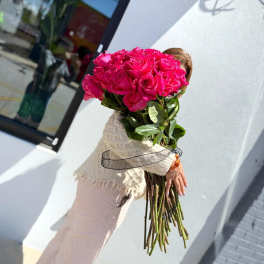 Large bouquet of hot pink roses held by a person outdoors