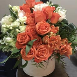 Orange and white roses with orange tulips in a white vase