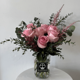 Pink roses in a clear glass vase with airy greenery