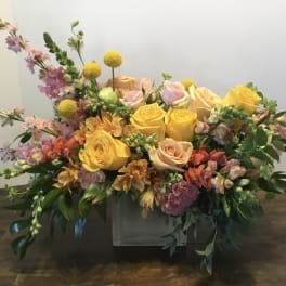 Mixed bouquet of yellow and pink roses in a low white container