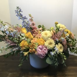 Mixed bouquet in a gray vase with yellow, pink, and blue flowers