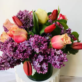 Bouquet of purple lilacs and pink tulips in a glass vase