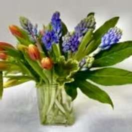 Bouquet of orange tulips and purple hyacinths in a clear glass vase