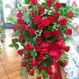 Standing spray of red roses with a large red ribbon