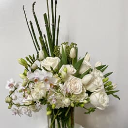 White floral arrangement in a clear glass vase with tall green stems