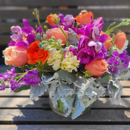 Bouquet of orange, pink, and purple flowers in a glass vase